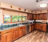 Wood-finish flooring, wood cabinetry, tile countertops, stainless steel sink, and stainless steel dishwasher
