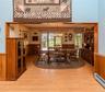 Wood-finish flooring throughout, with a dining area featuring wood wall paneling and a chandelier