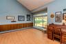 Vaulted ceiling, wood-finish flooring, wood paneling, large sliding glass windows, and built-in heat registers