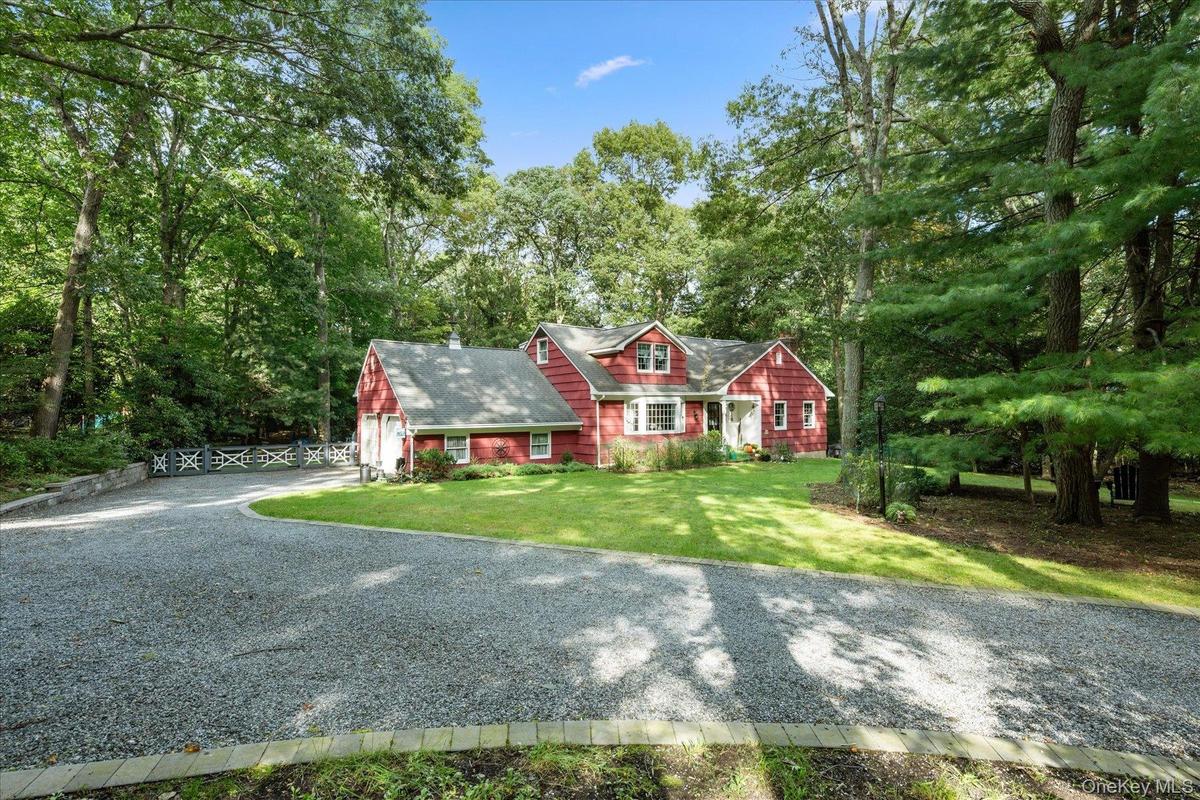 Red siding exterior with white trim, a gravel driveway, and a manicured lawn