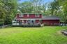 Expansive backyard with a manicured lawn, multi-level deck, and mature surrounding trees