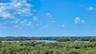 Elevated views extend across the lush coastal landscape toward the waters of Little Sarasota Bay.