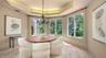 A beautifully defined dining room offers an intimate setting enhanced by a tray ceiling, chandelier and abundant natural light.