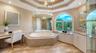 A soaking tub, generous vanity space and graceful architectural detailing create an elegant primary bath.