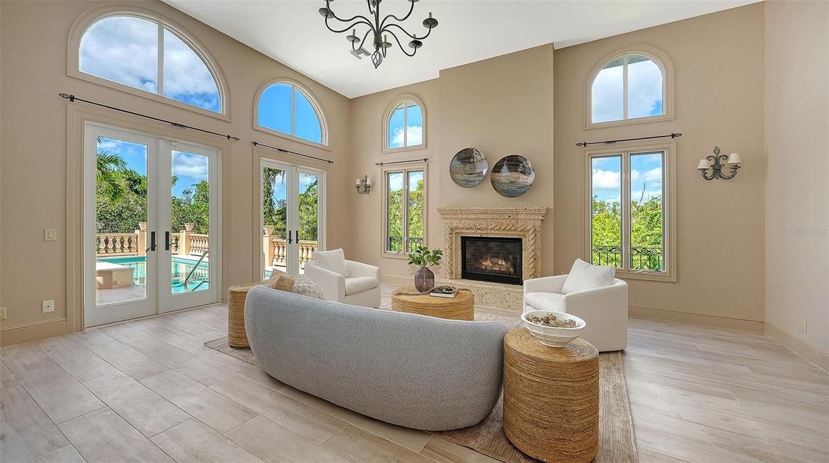 Walls of windows and French doors fill the great room with natural light while connecting the interior to the surrounding landscape.