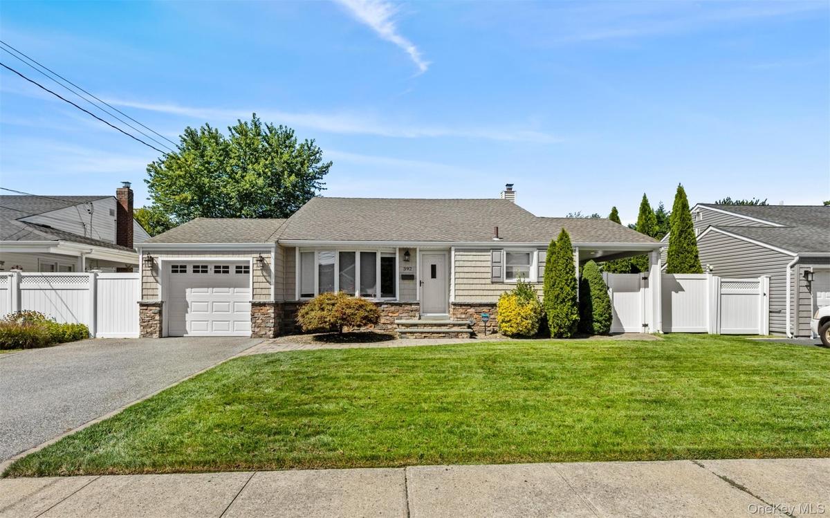 Ranch-style exterior with stone veneer accents, an attached garage, and a paved driveway