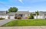 Ranch-style exterior with stone veneer accents, an attached garage, and a paved driveway