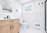 Modern bathroom featuring a wood-finish vanity with a white countertop and matte black fixtures