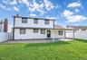 Expansive rear yard featuring a covered patio, manicured lawn, and privacy fencing