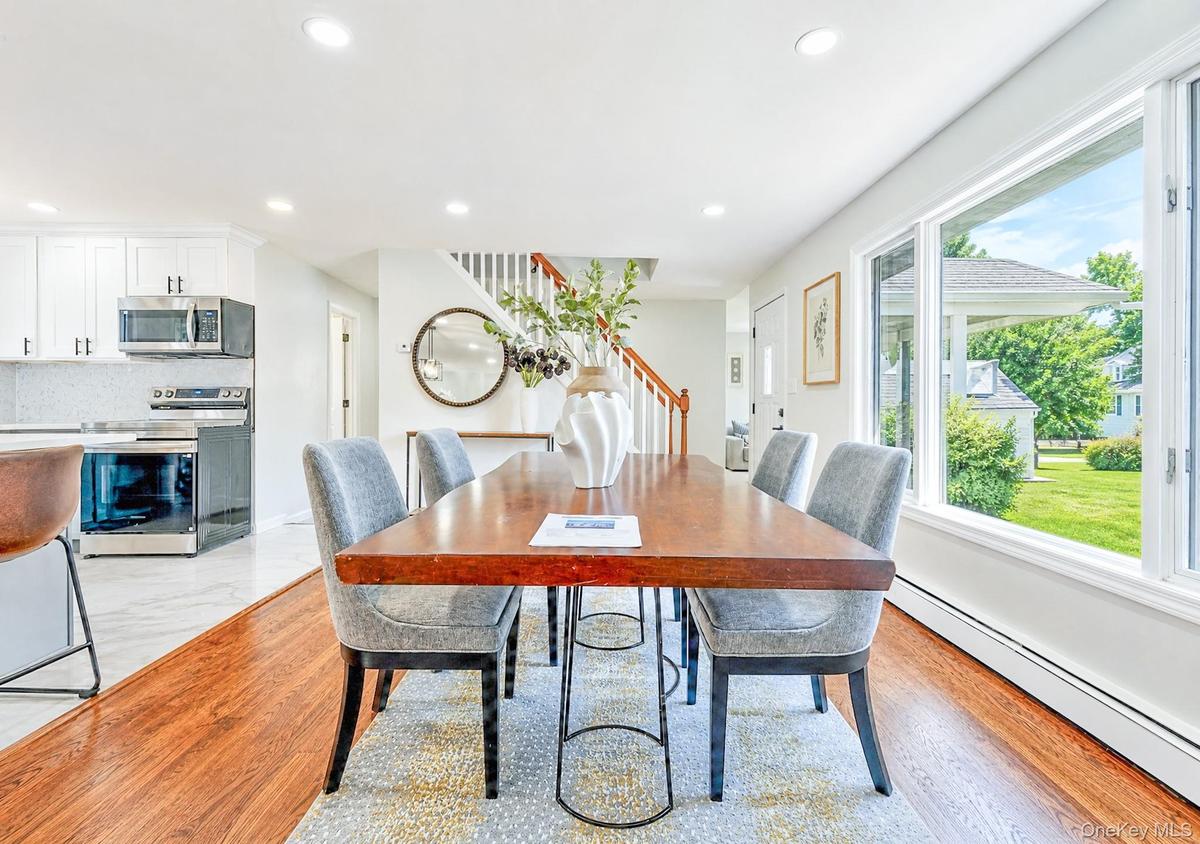 Spacious dining area featuring rich wood-finish flooring, abundant natural light from large windows, recessed lighting, and an open concept layout