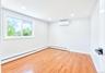 Light-filled room featuring wood-finish flooring, a white trim window, baseboard heating, recessed lighting, and a wall-mounted climate control unit