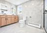 Bathroom featuring a double vanity with wood-finish cabinetry and rectangular illuminated mirrors