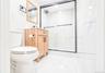 Bathroom featuring a frameless glass shower enclosure with matte black trim, a wood-finish vanity with ample storage, a rectangular wood-framed mirror