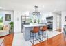 Modern kitchen featuring a central island with a light countertop, white shaker cabinetry, stainless steel appliances, and a mosaic tile backsplash