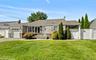 Ranch-style exterior with stone veneer and shingle siding, an attached garage, a covered carport, and a paved driveway