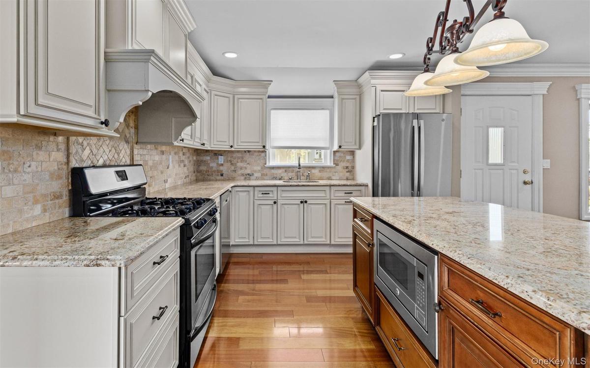 Hardwood flooring, light-toned cabinetry, and stone countertops