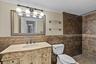 Ornate vanity with integrated sink, bronze-tone faucet, and custom tile backsplash, walk-in shower, crown molding