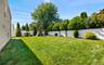 Expansive lawn area, white privacy fencing, and mature perimeter landscaping, fully fenced and In-ground speakers