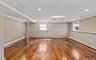 Cherry wood finish flooring, three windows with white trim, recessed lighting, crown molding, and chair rail detailing