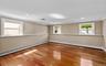 Cherry wood finish flooring, three windows with white trim, recessed lighting, crown molding, and chair rail detailing