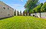 Expansive green lawn with a white privacy fence and mature perimeter plantings