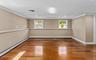 Cherry wood finish flooring, three windows with white trim, recessed lighting, crown molding, and chair rail detailing