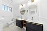 Dual floating vanities with integrated sinks, round back-lit mirrors, brushed gold fixtures and tub/shower combo
