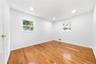 Hardwood flooring, recessed lighting, white walls, and two windows with white trim