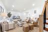 Bright living area featuring wood-finish flooring, recessed lighting, and a prominent staircase with wood handrail and black balusters