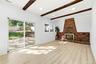 Wood-finish flooring, exposed ceiling beams, brick fireplace with metal insert, recessed lighting, and sliding glass door to a private outdoor space