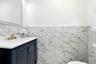 Dark-toned vanity with brushed gold-finish hardware, a white countertop, and an integrated rectangular sink and toilet.