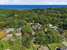 Expansive wooded landscape with residential properties and a visible body of water