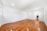 Expansive room featuring rich wood-finish flooring, recessed lighting, white walls, and multiple windows. Double closet leading to primary bathroom.Al