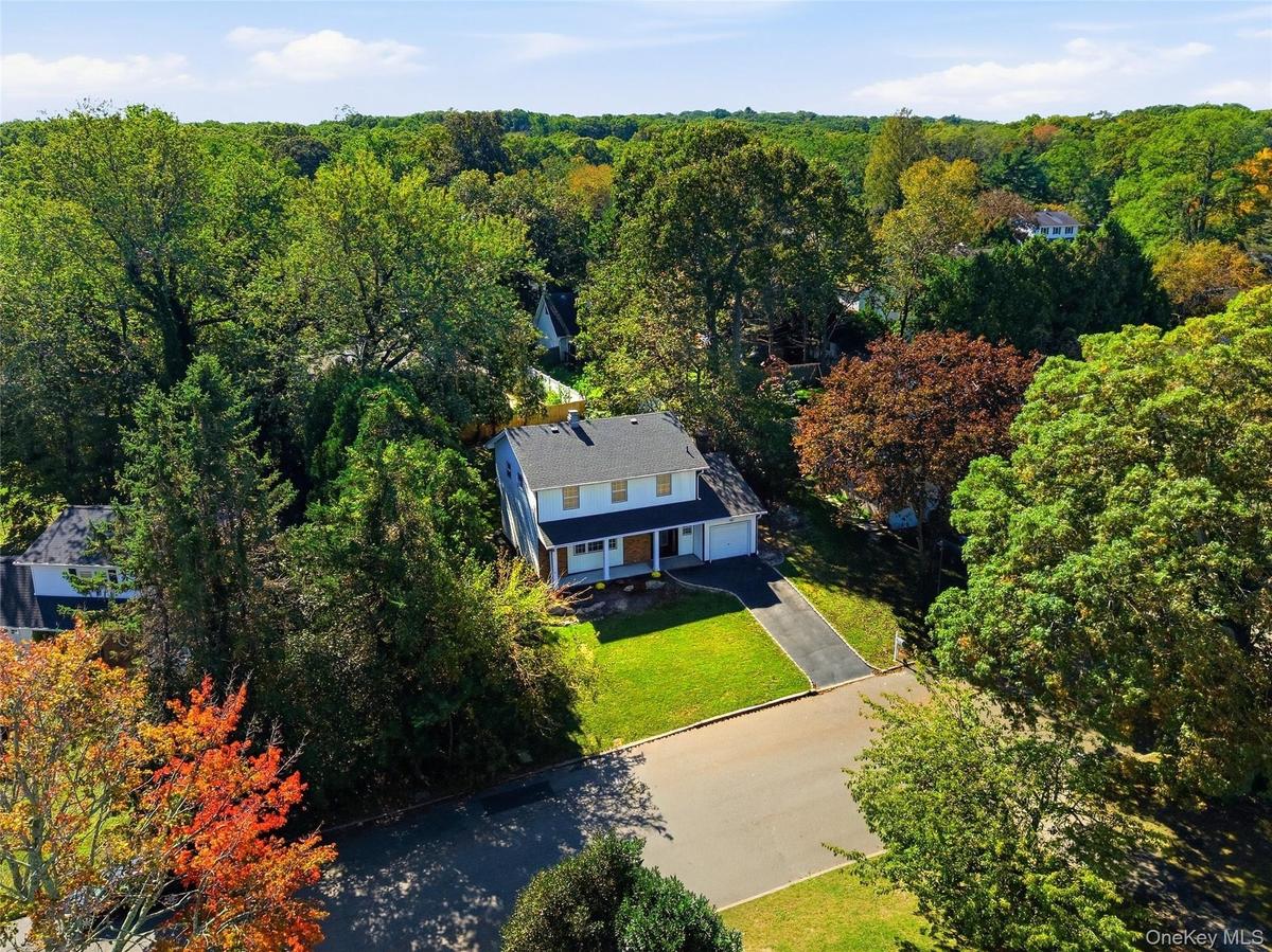 Two-story residence with a dark shingle roof, light-colored siding, and a paved driveway