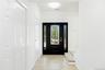 Black entry door with decorative glass side panels, wood-finish flooring, two white paneled closet doors, and a half bathroom
