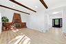 Exposed wood beams, recessed lighting, brick fireplace with metal insert, wood-finish flooring, and a dark-paneled entry door with decorative glass in