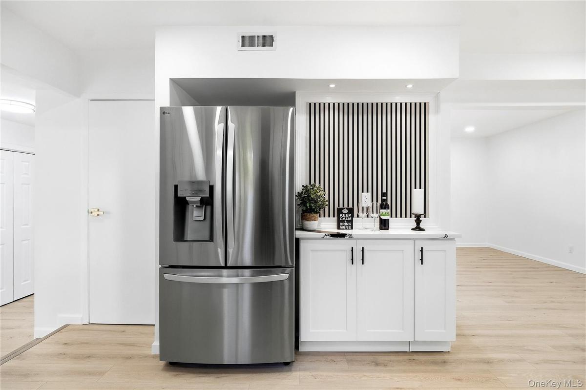 Stainless steel French door refrigerator with bottom freezer and integrated ice/water dispenser. Wine/coffee bar.