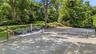 Private tennis court with surrounding mature trees and landscaping