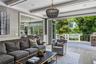 Expansive living area with gas fireplace opening to a large outdoor deck with a stone-clad built-in grill and cable railing