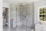Glass-enclosed shower with marble tile