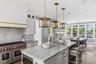 Gourmet kitchen with professional grade stainless steel range, custom cabinetry, large central island with seating, and ample natural light through ex