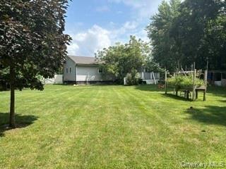 Expansive green lawn with mature trees and a raised garden bed