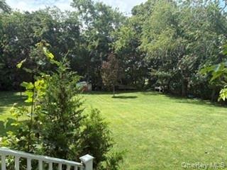 Expansive green lawn with mature perimeter trees and white baluster railing