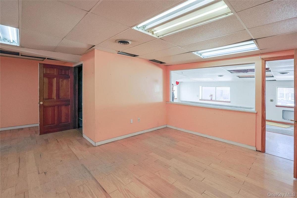 Empty room featuring light wood-type flooring and a drop ceiling