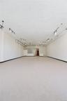 Expansive open-concept room with light-colored flooring, white walls, and track lighting fixtures