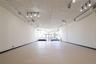 Expansive open-concept room with light-colored flooring, white walls, and track lighting fixtures