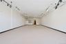 Expansive open-concept room with light-colored flooring, white walls, and track lighting fixtures