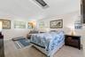 The generously sized primary bedroom feels bright and airy with multiple windows, a skylight overhead, neutral tones, and luxury vinyl plank flooring 