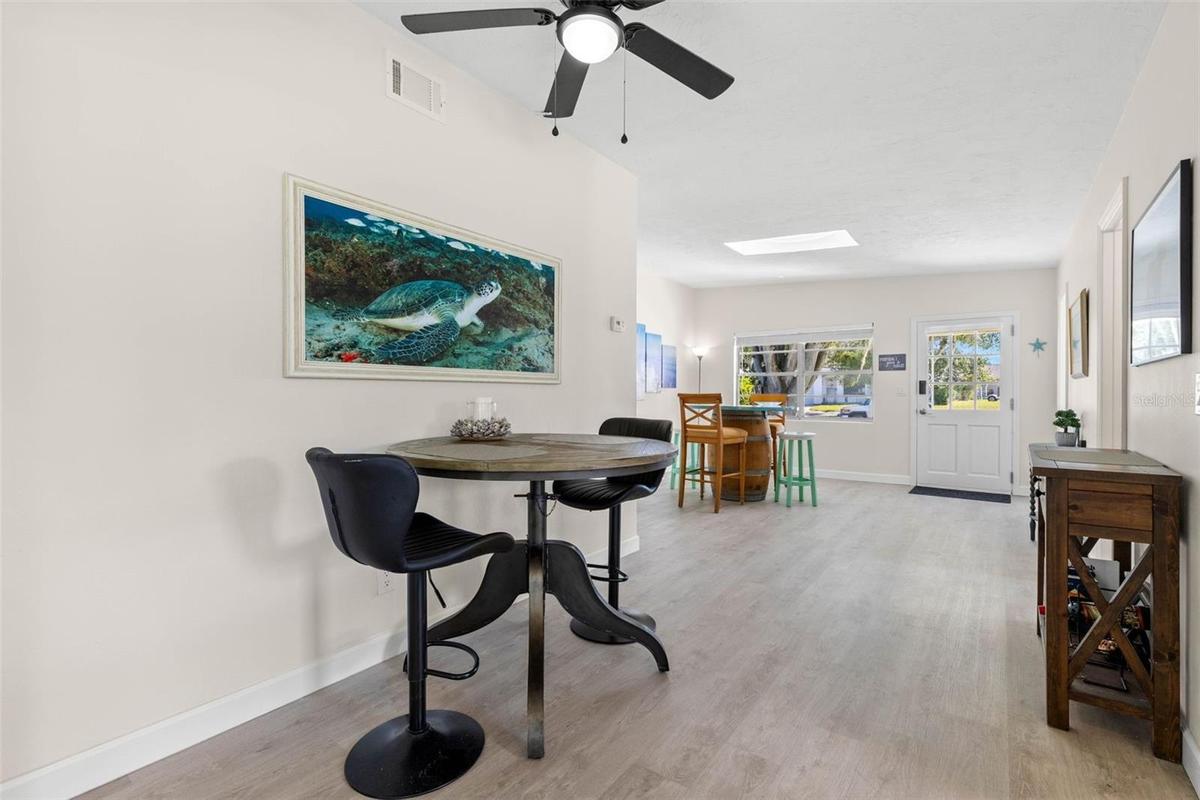 A flexible casual dining area features neutral tones, 2025 luxury vinyl plank flooring, and a ceiling fan, with an open layout that easily accommodate