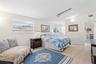 The spacious primary bedroom easily accommodates a king-size bed and a dedicated sitting area, with multiple windows, a skylight, neutral tones, and l